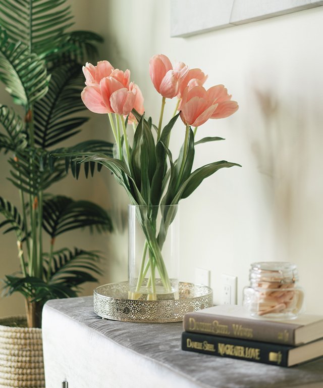 Pink tulips in glass vase on a mantel with books